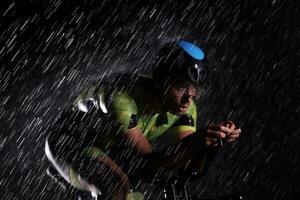 Triathlon-Athlet, der in regnerischer Nacht schnell Fahrrad fährt foto
