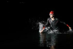 Triathlon Athlet Fertigstellung Schwimmen Ausbildung beim dunkel Nacht foto