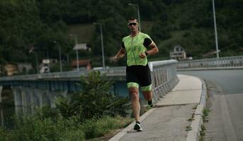 Triathlonsportler, der auf der Straße läuft foto