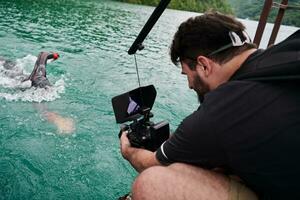 Videofilmer, der einen Triathlon-Schwimmsportler fotografiert foto