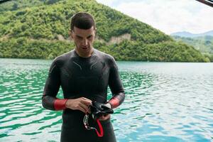 Triathlon-Athlet bereitet sich auf das Schwimmtraining auf dem See vor foto