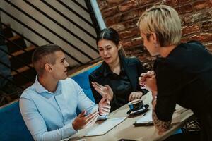 glücklich Geschäftsleute lächelnd fröhlich während ein Treffen im ein Kaffee Geschäft. Gruppe von erfolgreich Geschäft Profis Arbeiten wie ein Mannschaft im ein multikulturell Arbeitsplatz. foto