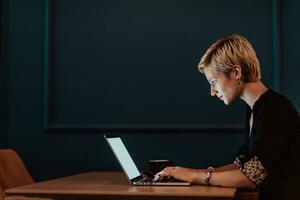 Geschäftsfrau Sitzung im ein Cafe während konzentriert auf Arbeiten auf ein Laptop und teilnehmen im ein online Sitzungen. selektiv Fokus. hoch Qualität Foto