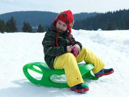 glücklicher kleiner junge hat spaß im winterurlaub auf frischem schnee foto