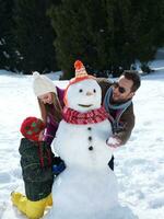 glückliche Familie, die Schneemann macht foto