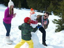 glückliche Familie, die Schneemann macht foto