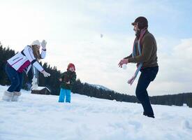 glückliche Familie, die im Winter zusammen im Schnee spielt foto