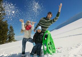 familie, die spaß auf frischem schnee im winterurlaub hat foto