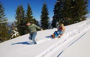 familie, die spaß auf frischem schnee im winterurlaub hat foto