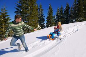 familie, die spaß auf frischem schnee im winterurlaub hat foto