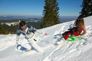 familie, die spaß auf frischem schnee im winterurlaub hat foto