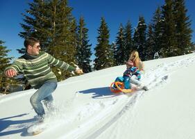 familie, die spaß auf frischem schnee im winter hat foto