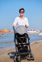 Mutter am Strand spazieren und Kinderwagen schieben foto