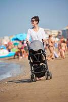 Mutter am Strand spazieren und Kinderwagen schieben foto