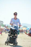 Mutter am Strand spazieren und Kinderwagen schieben foto