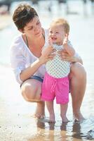 Mama und Baby am Strand haben Spaß foto