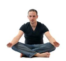 junger Mann im Lotussitz, der Yoga ausübt foto