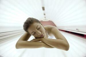 schöne junge Frau im Solarium bräunen foto