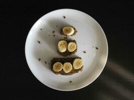 Banane Sandwiches auf ein Weiß Teller auf das schwarz Tabelle foto