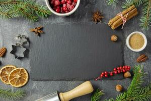 kulinarisch Hintergrund mit Weihnachten Winter Gewürze und Zutaten zum Backen auf dunkel Stein Tabelle mit ein schwarz Schiefer, Tafel Attrappe, Lehrmodell, Simulation zum Ihre Text. oben Sicht. Kopieren Raum. foto