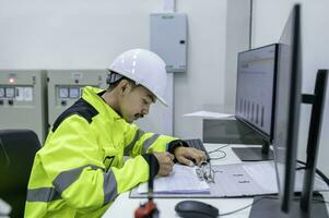 elektroingenieurmann, der die spannung am stromverteilerschrank im kontrollraum überprüft, jährliche vorbeugende wartung, thailand-elektriker, der im unternehmen arbeitet foto