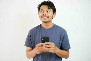 jung asiatisch Mann Träumer Sehen Traum leeren Raum Denken Buchung Botschaft halten Telefon isoliert auf Weiß Hintergrund foto