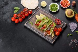 mexikanische Tacos mit Rindfleisch, Tomaten, Avocado, Zwiebeln und Salsasauce foto