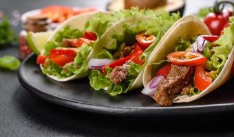 mexikanische Tacos mit Rindfleisch, Tomaten, Avocado, Zwiebeln und Salsasauce foto