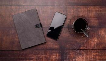 Kaffeetasse, Buch, Smartphone auf dem Schreibtisch. foto