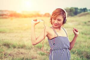 schöne frau mit stehend hörender musik in den blumenfeldern. foto