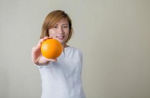 Porträt des hübschen Frauenlächelns, das orange Frucht hält foto