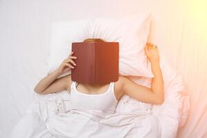 junge Frau schläft auf dem Bett nach mit Gesicht bedeckt durch das Buch. foto