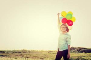 Frau steht mit bunten Luftballons im Feld und Smiley
