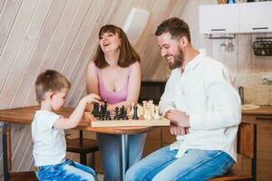 glücklich Familie Mutter, Papa und ihr Sohn spielen Schach im das Zimmer foto