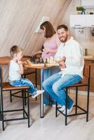 glücklich Familie spielen Schach im das Küche foto