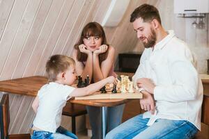 glücklich Familie Mutter, Papa und ihr Sohn spielen Schach im das Zimmer foto