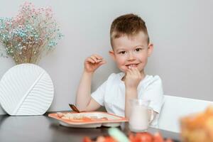 Lachen Junge isst köstlich Pasta beim das Tabelle im das Küche foto