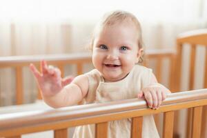 Porträt von ein glücklich und Lachen Baby im ein Krippe foto