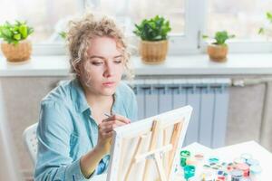 lockig blond Frau Gemälde ein Bild durch das Fenster foto