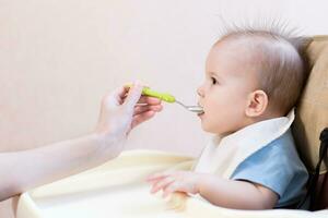 Mutter gibt Baby Essen von ein Löffel foto