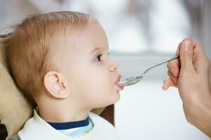 Mutter gibt Baby Essen von ein Löffel foto