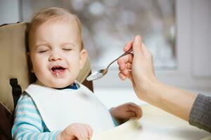 Mutter gibt Baby Essen von ein Löffel foto