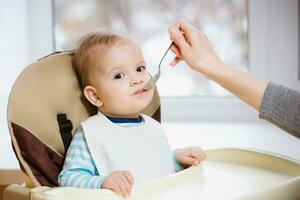 Mutter gibt Baby Essen von ein Löffel foto