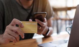Online-Zahlung, die Hände des Mannes, die Smartphone halten und Kreditkarte verwenden foto