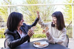 jung multiethnisch weiblich freunde Essen ein Pizza draußen foto