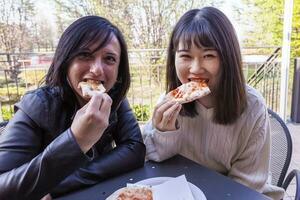 jung Freundinnen multiethnisch Frauen Essen Pizza foto