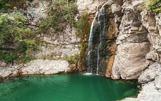 wunderbar klein Wasserfall Das Formen ein Teich von Smaragd Wasser im ein Wald foto