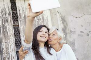 Mutter und Erwachsene Tochter nehmen ein Selfie draußen foto