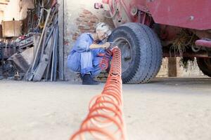 mechanisch reifen weiblich bläst auf das Reifen von das Traktor foto