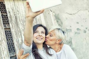 Mutter und Erwachsene Tochter nehmen ein Selfie draußen foto